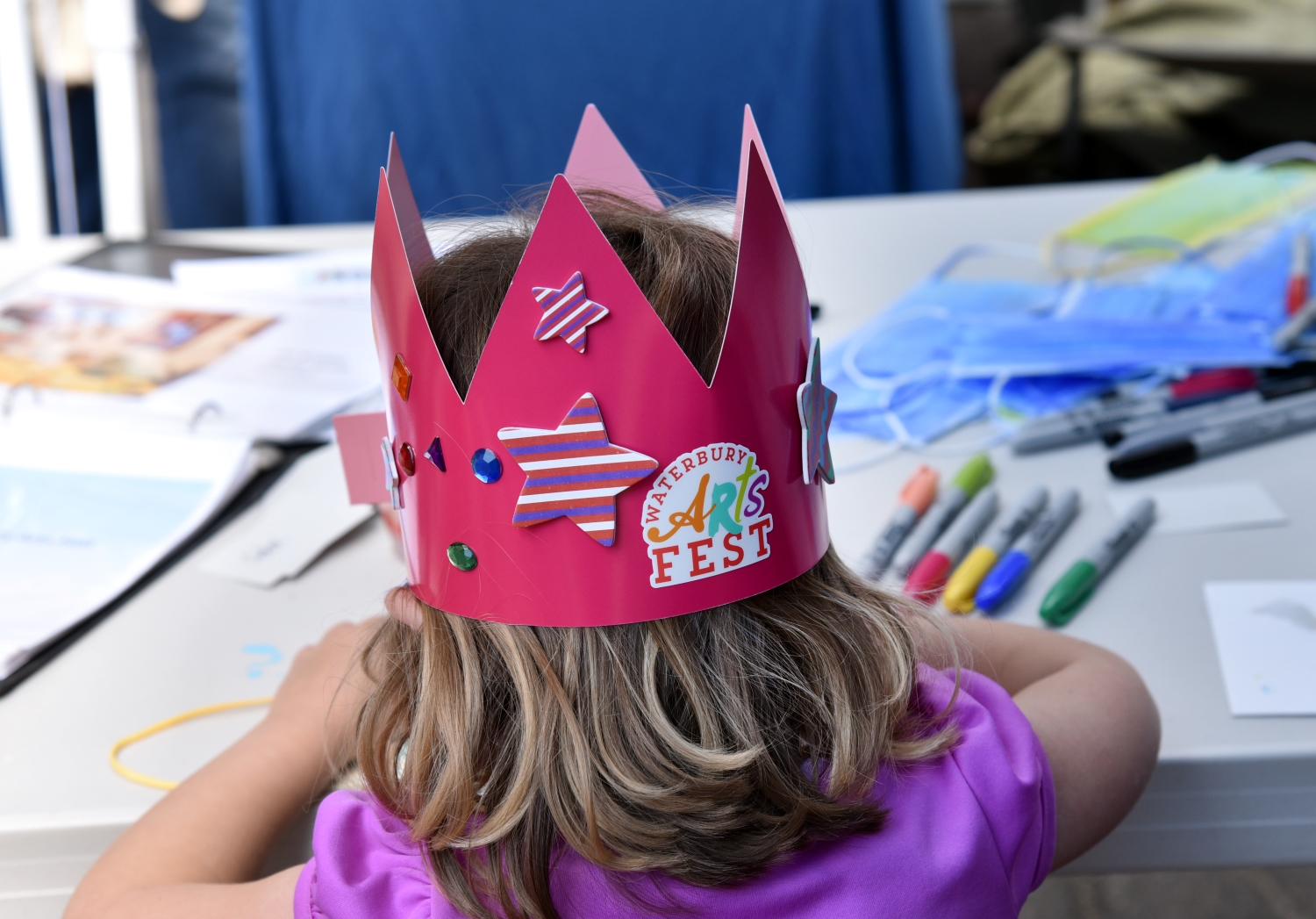Kid at an activity station with a Waterbury Arts Fest crown